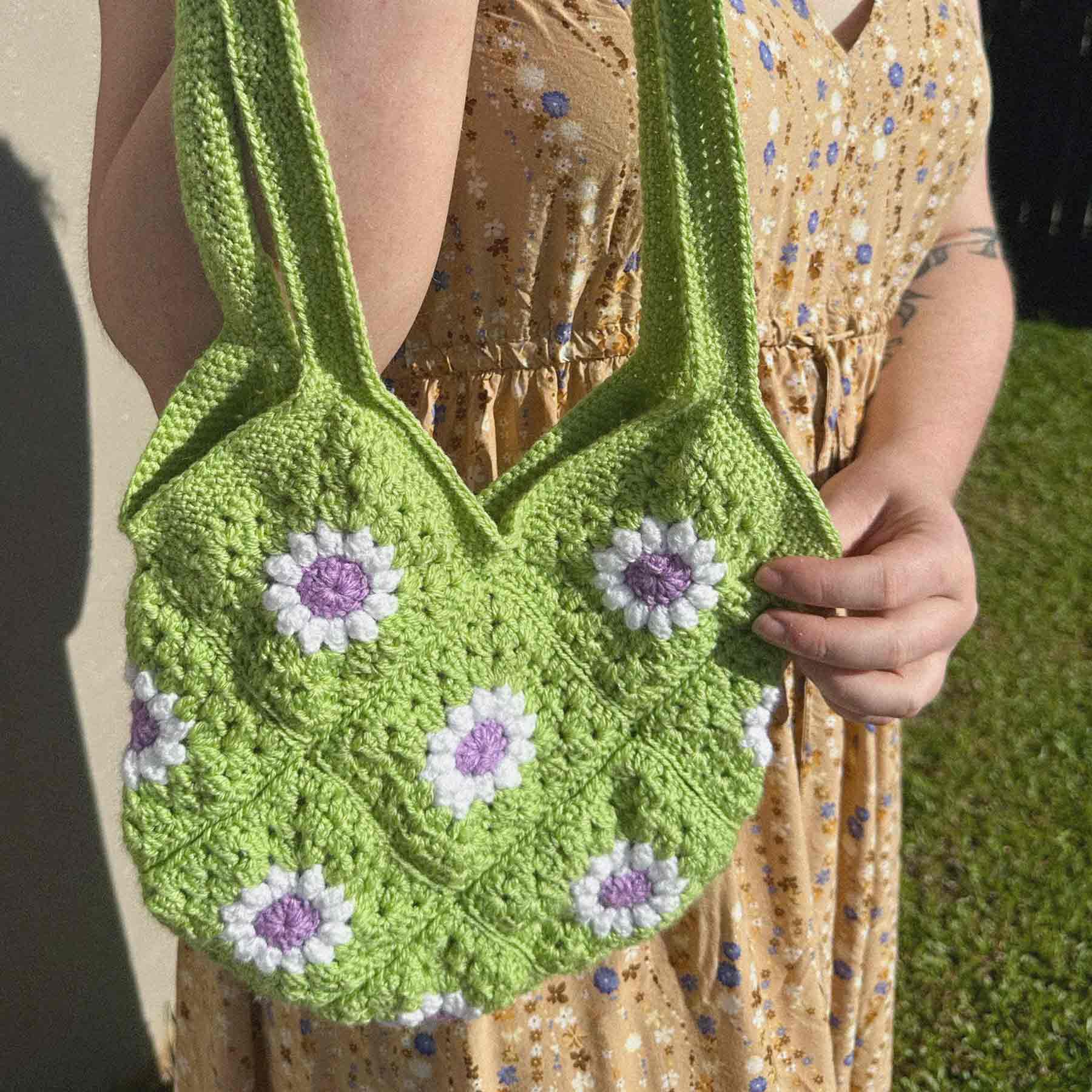 Green crochet bag with white and purple daisies on it